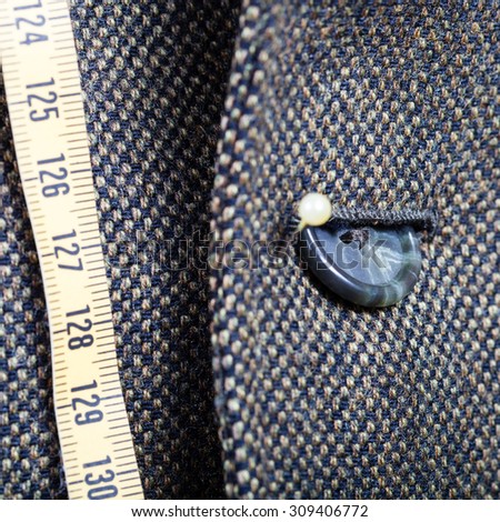 tailor measure tape and half buttoned button on green jacket close up