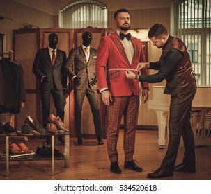 Tailor measuring client for custom made suit tailoring