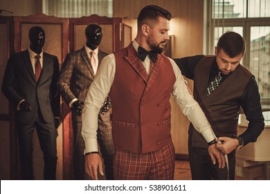 Tailor measuring client for custom made suit tailoring