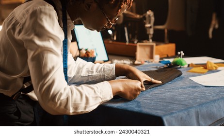 Tailor measuring fabric in workshop, checking material measurements, custom made clothing line. Employee working on luxury fashion collection in fashion atelier. Handheld shot. Close up.