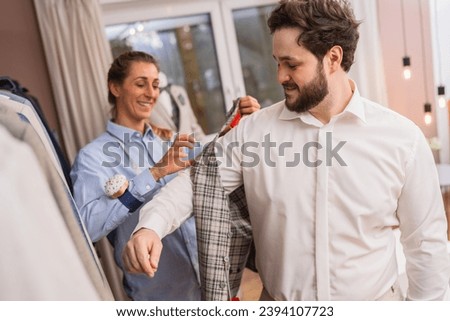 Tailor measuring a jacket on a client in a suit store