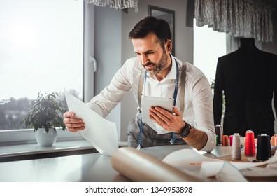 Tailor over work desk using digital tablet during work, modern fashion designer at workshop