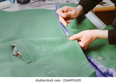 A tailor stabs coat with a needle. Outerwear sewing. Clothing repair. Tailoring. Close up view