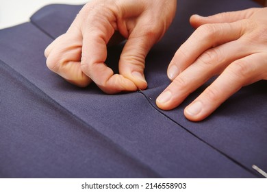 A tailor stabs a fabric with a needle. Clothes sewing. Clothing repair. Tailoring. Close up view