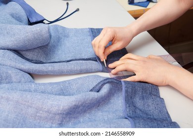 A tailor stabs a trouser leg with a needle. Clothes sewing. Clothing repair. Tailoring. Close up view