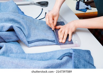 A tailor stabs a trouser leg with a needle. Clothes sewing. Clothing repair. Tailoring. Close up view