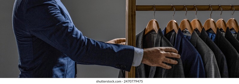 Tailor, tailoring. Stylish men's suit. Man suit, tailor in his workshop. Fashion man in costume suit. Man choosing jacket in his wardrobe. - Powered by Shutterstock