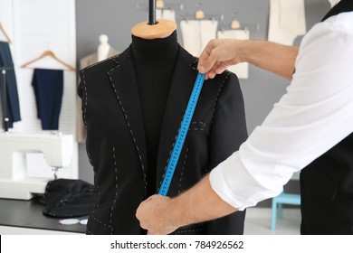 Tailor taking measurements of mannequin in atelier