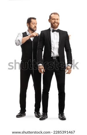 Tailor taking measures for a groom suit isolated on white background