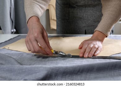 Tailor transferring sewing pattern onto fabric with tracing wheel in atelier, closeup - Powered by Shutterstock