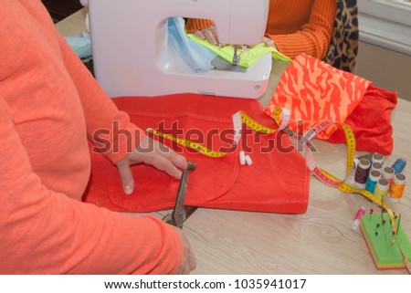 Tailor Woman, fashion designer working at studio. Fashion designer cutting textile next to a sewing machine