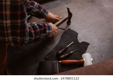 Tailor woman processing hammers seam on leather goods, top view. Concept handmade craftsman on workplace. - Powered by Shutterstock