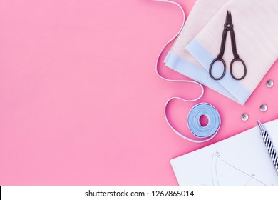 Tailor work place with thread, scissors, fabric. Sewing as hobby. Pink background top view space for text