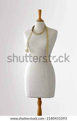 Tailor's fashion dummy with a tape measure on a white background