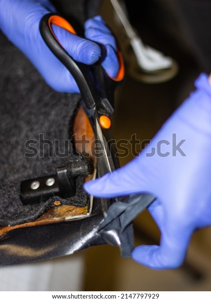 Tailor\'s hands in blue, rubber gloves while\
working with fabric.Tightening of the car interior.The hands of a\
girl in blue gloves while working with scissors with fabric\
selective focus.