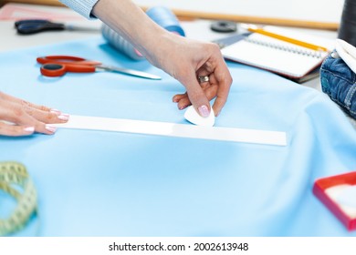 The tailor's hands are marking the pattern with chalk. Sewing and design of clothes.