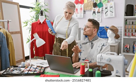 Tailors working together in a design room surrounded by fashion sketches, fabrics, and a sewing machine. - Powered by Shutterstock