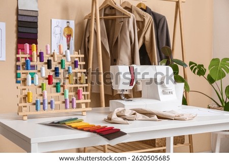 Tailor's workplace with sewing machine, thread spools and fabric samples in atelier