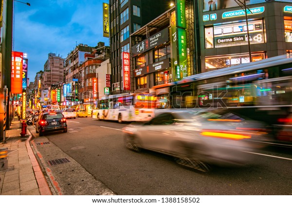 Taipei, Taiwan\
- April 12, 2019: Motion blur of Taiwanese bus passing through\
Chengdu road in front of Ximending Shopping district during the\
dusk with neon sign in the background\

