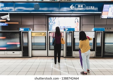 Taipei, Taiwan - April 13, 2019: People Waiting For The Next Metro Train On Bannan Line (Blue Line) As One Is Leaving In Motion Blur