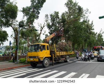 Taipei/Taiwan - 3 Sept 2015: Tree Pruning Rue Caulaincourt. Workers Gather Branches And Cut Leaves On Sidewalk. A Worker Stands On Truck Crane.