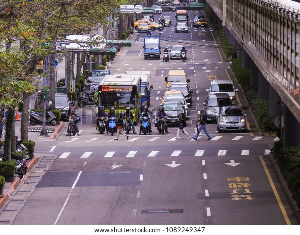 Taipei,Taiwan-April 16,2018:When the traffic signal\
turns red on the straight asphalt road, all vehicles stop at the\
intersection and pedestrians walk on the zebra crossing.Taipei city\
traffic \
view.