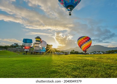 Taitung, Taiwan - August 29, 2021: Various Shape Balloons With Beautiful Sunrise And Green Grass At Luye Highland, Taiwan International Balloon Festival