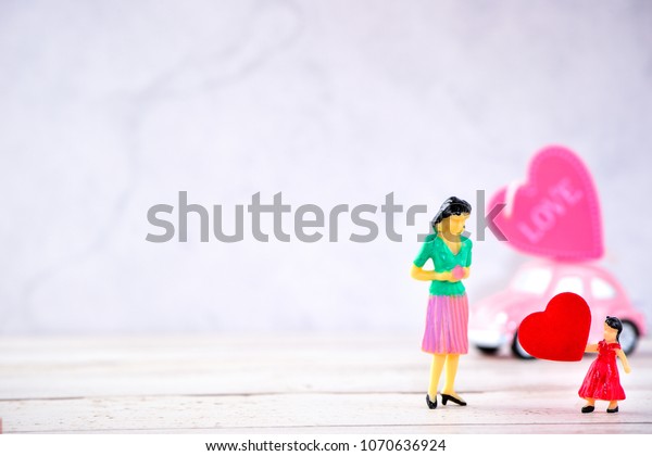 Taiwan, Tainan - April 17, 2018:  Miniature people:\
A mother who is given a heart in love by little child girl with\
little bettle pink car, the concept of Mother\'s Day, blank\
background for text,\
macr
