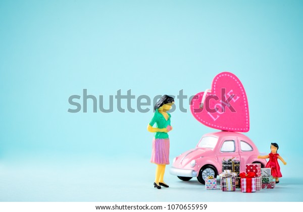 Taiwan, Tainan - April 17, 2018: Miniature people: A\
mother who is given a heart in love and gifts by little child girl\
with little bettle pink car, the concept of Mother\'s Day, blank\
background for t