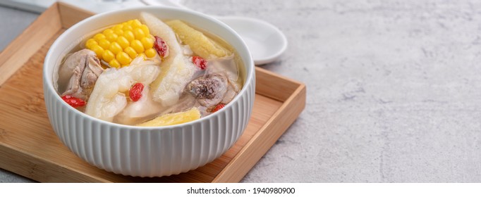 Taiwanese Homemade Delicious Chicken Soup Food In A Bowl With Pineapple, Bitter Gourd And Sweet Corn On Cement Gray Table Background.