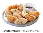 Taiwanese and Japanese Pan-fried gyoza dumpling jiaozi food in a plate isolated on white background.