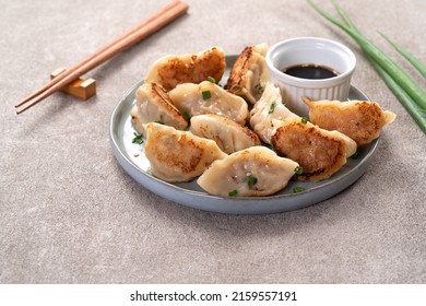 Taiwanese and Japanese Pan-fried gyoza dumpling jiaozi food in a plate with soy sauce on gray table background.