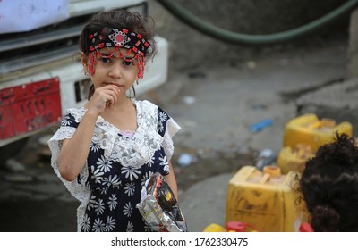 Taiz  Yemen - 23 June 2020 : A Yemeni girl wears traditional dress and waits for her turn to fill the water due to the water crisis in the Yemeni city of Taiz.
