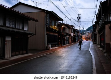 Takayama, Japan - April 8, 2019: Town In Gifu In Traditional Village At Night With Illuminated Lantern Lamps And Woman Crossing Street Road