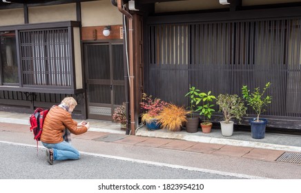 Takayama/Japan - November 18, 2019: A Tourist Is Admiring A Small Container Garden.