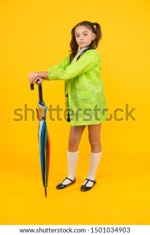 Take the accessory and let it rain. Small child holding colorful umbrella rain accessory. Little girl in raincoat with fashion accessory for rainy autumn season. The perfect accessory to keep her dry.