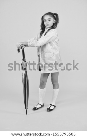 Take the accessory and let it rain. Small child holding colorful umbrella rain accessory. Little girl in raincoat with fashion accessory for rainy autumn season. The perfect accessory to keep her dry.