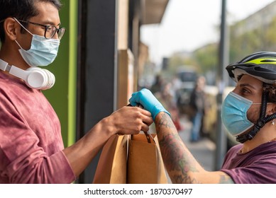 take away food delivery time, the customer receives from the delivery man two envelopes with his meal, home delivery, new business concept in time of epidemic, use of protective masks and gloves - Powered by Shutterstock