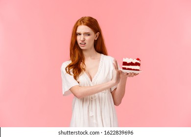 Take It Away, Gross. Ignorant And Picky Spoiled Redhead Birthday Girl Refusing Eating Dessert, Holding Plate With Cake And Making Stop, Rejection Gesture, Turn Away With Disgust, Pink Background