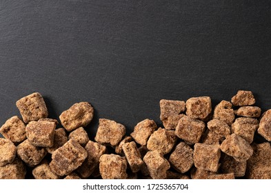 Take a bird's eye view of a block of brown sugar placed on a black background with copy space
