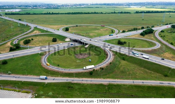 Take a bird\'s eye view of the\
flyover and traffic intersections of a modern city on a summer day.\
Modern design of the roadway to avoid traffic jams. Few\
cars.