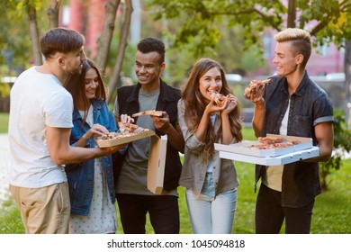 Take a bite of pizza. Young friends sharing delicious pizza, hangin out, Friday party in the park.