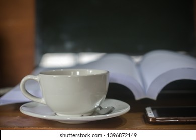 Take a break Concept,University coffee shop,Coffee and books on the desk.Tired of reading texts.Stimulating the body with caffeine.Turn off your smartphone and laptop to relax.Hot latte in white cup. - Shutterstock ID 1396872149
