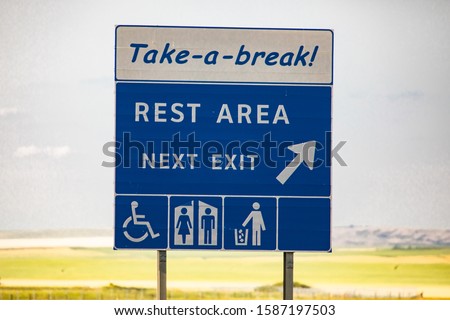 take a break, Rest area in the next exit, Tidy man, toilets, Special needs symbols., Information Road blue Sign against yellow prairies and plains