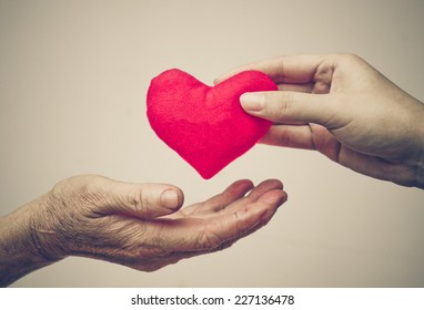 Take Care Of Old Mother - Young Female Hand Giving A Red Heart To Old Hand Of A Mother - Happy Mother's Day