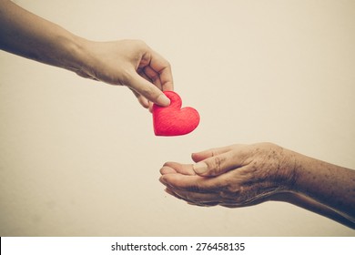 Take Care Of Old Mother - Young Female Hand Giving A Red Heart To Old Hand Of A Mother