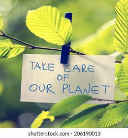 Take Care of our Planet concept with a handwritten note attached to a twig of fresh green sunlit leaves by a wooden clothes peg depicting the conservation of the ecology and natural resources.