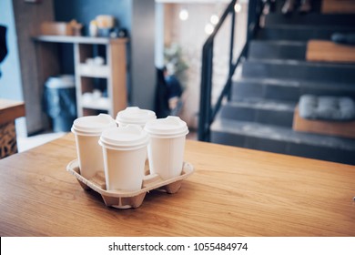 Take coffee to work for the entire office. High angle shot of a cardboard take out tray with four coffee cups with lids.
