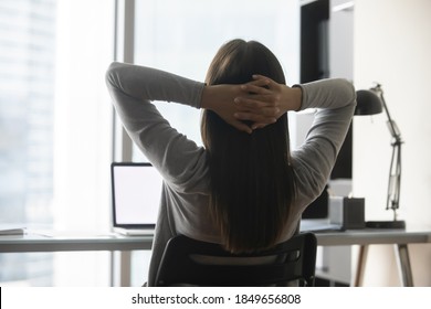 Take In Easy. Back View Of Tranquil Young Female Office Worker Manager Student Leaning Back On Chair With Hands Over Head Taking Break Pause In Working At Computer Looking At Window Resting Relaxing