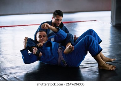 Take It To The Mat. Full Length Shot Of Two Young Male Athletes Sparring On The Floor Of Their Dojo.